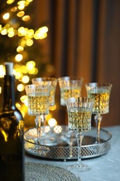 Photo of Tasty white wine in glasses on table against blurred lights. Bokeh effect