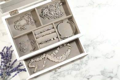 Photo of Many beautiful accessories in jewelry box and lavender on white marble table, flat lay