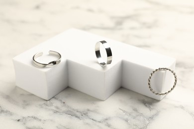 Photo of Composition with stylish rings on white marble table, closeup