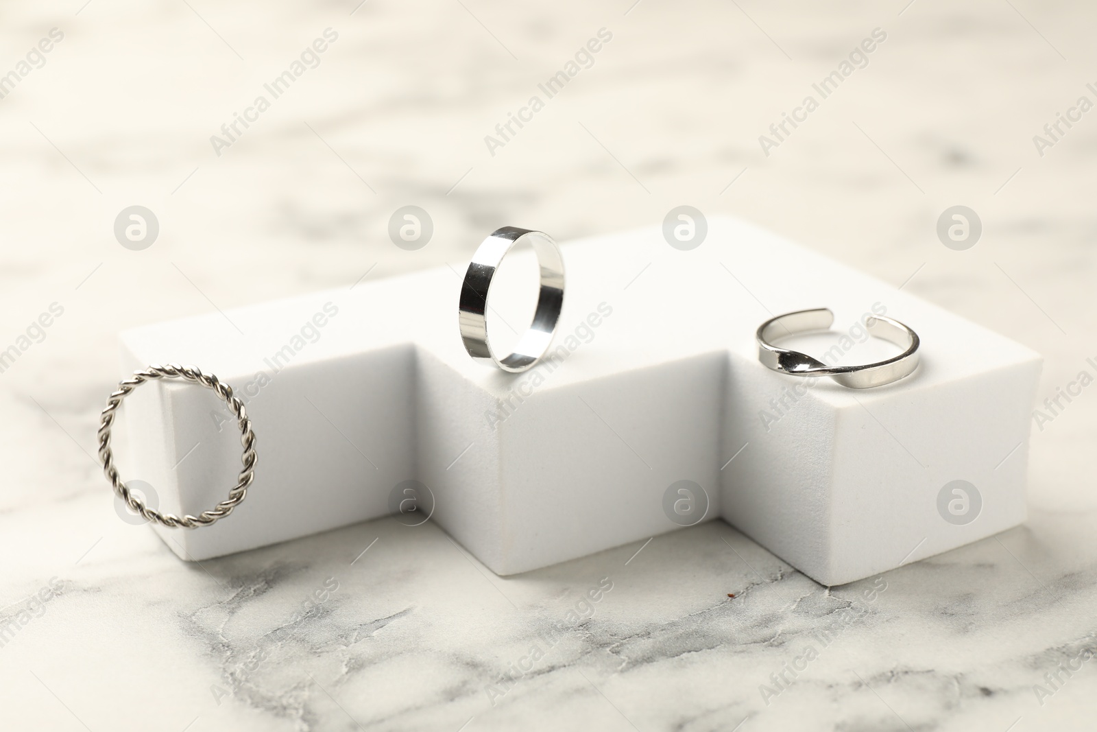 Photo of Composition with stylish rings on white marble table, closeup