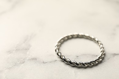 Photo of One stylish ring on white marble table, closeup. Space for text