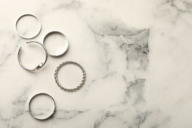 Photo of Many beautiful rings on white marble table, flat lay. Space for text