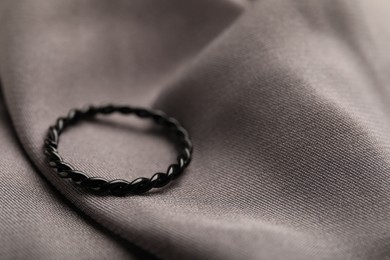 Photo of One stylish ring on grey cloth, closeup