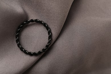 Photo of One stylish ring on grey cloth, top view