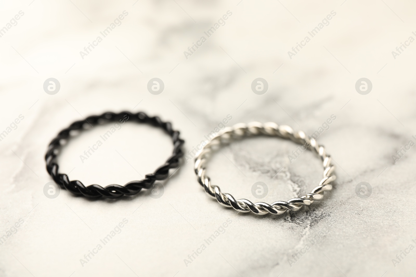 Photo of Stylish rings on white marble table, closeup