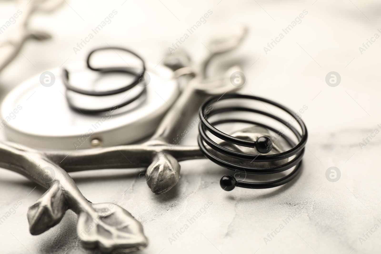 Photo of Stylish presentation of rings on white marble table, closeup