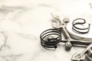 Photo of Stylish presentation of rings on white marble table, closeup. Space for text