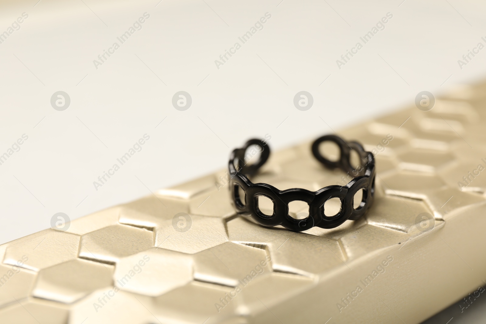 Photo of Stylish presentation of ring on golden textured surface, closeup