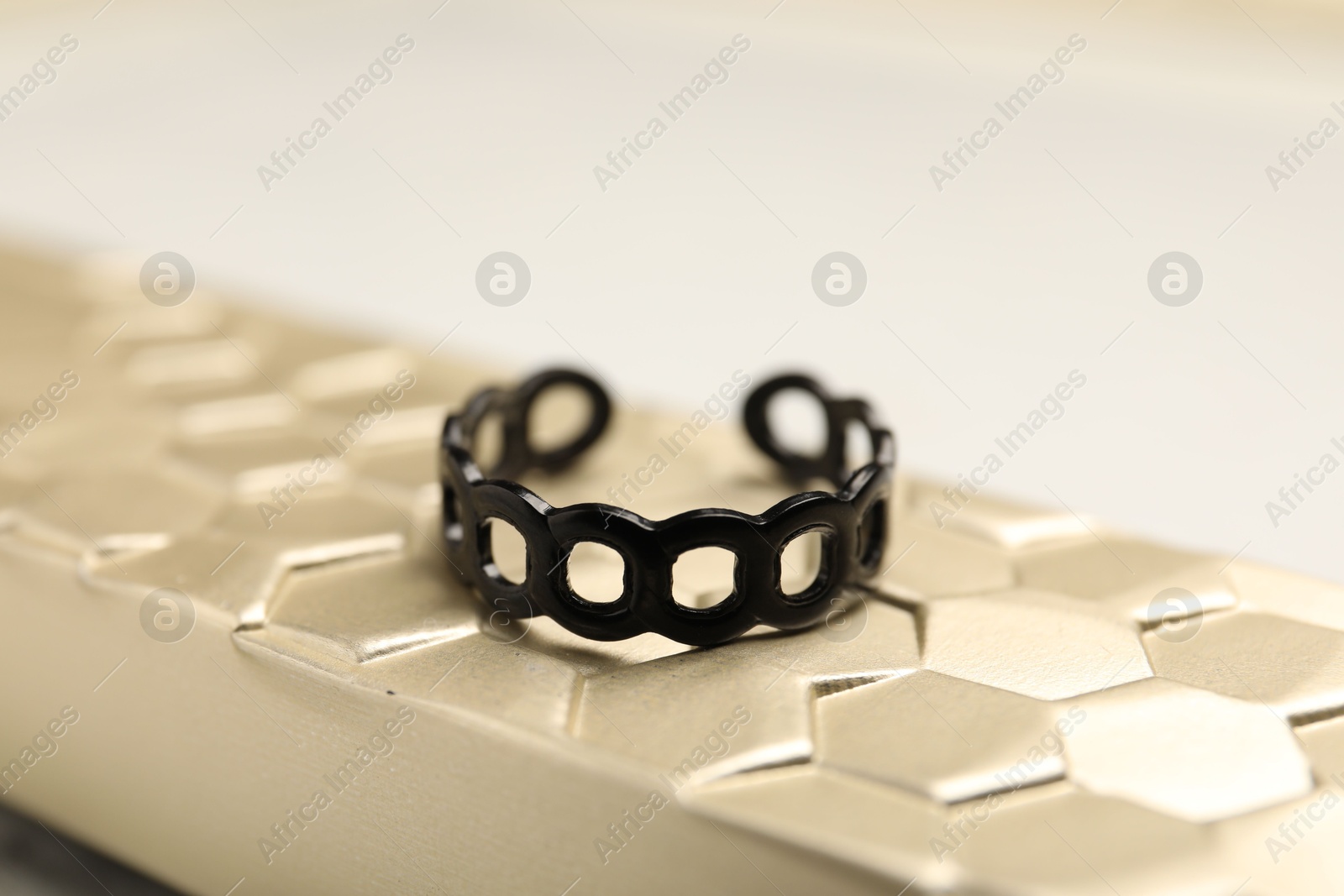 Photo of Stylish presentation of ring on golden textured surface, closeup