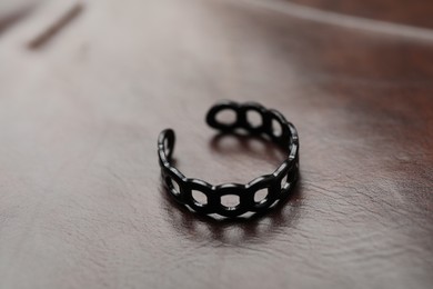 Photo of One black ring on leather surface, closeup