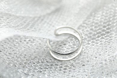 Photo of One stylish ring on light textured surface, closeup