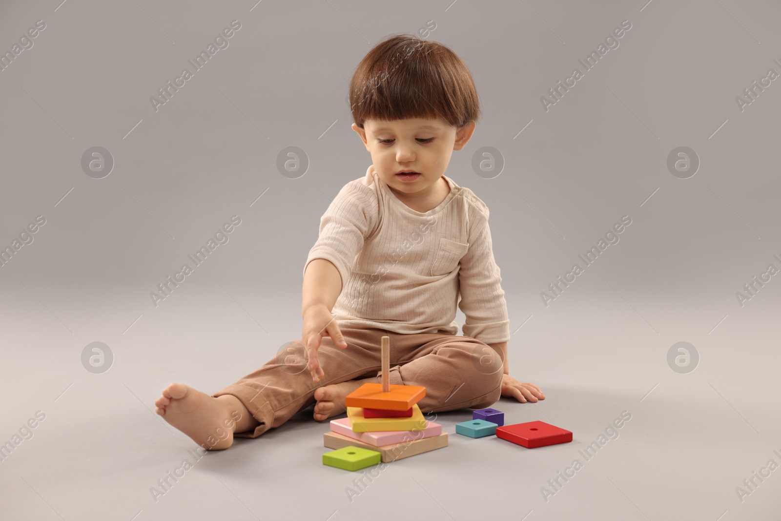 Photo of Cute little boy playing on grey background