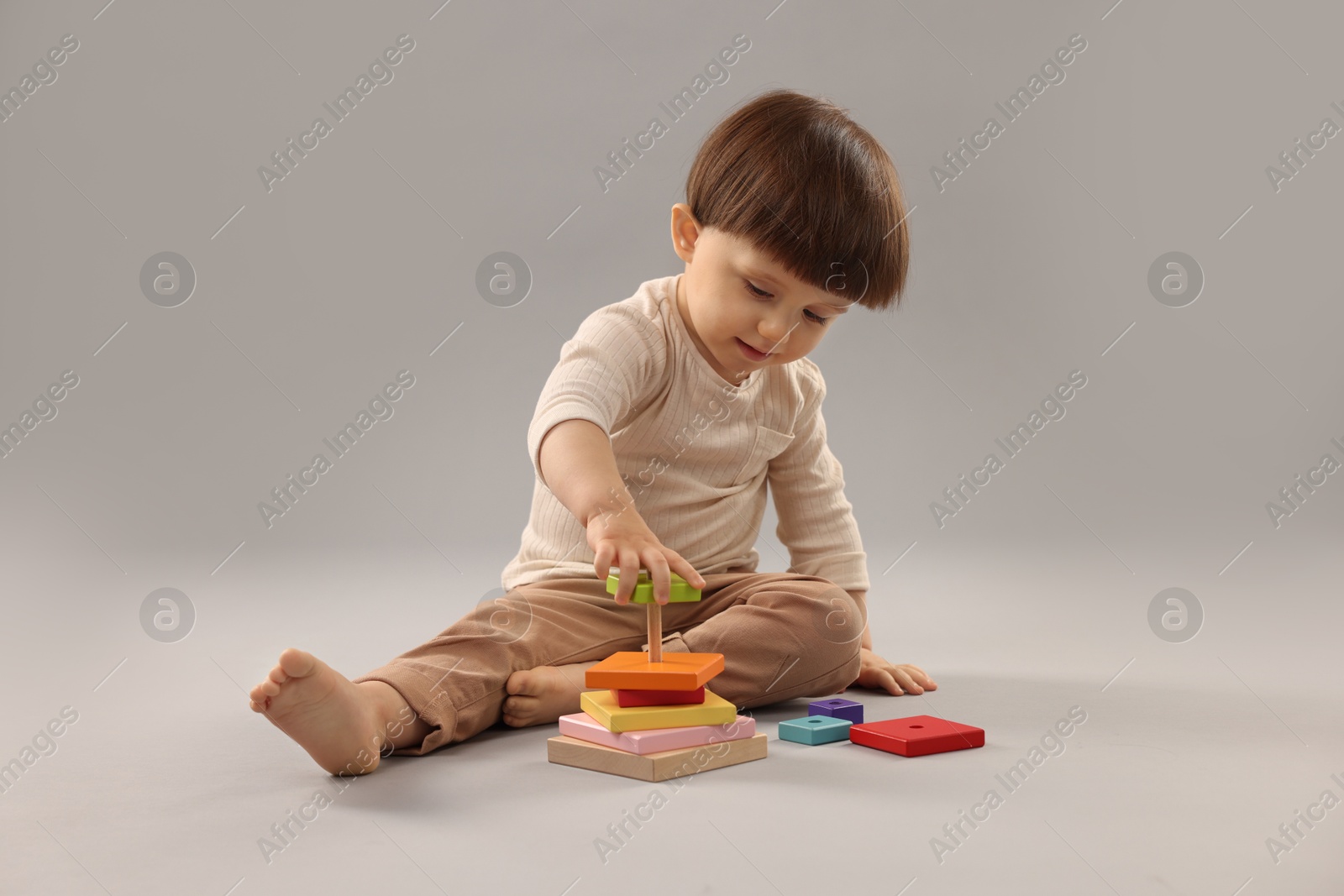 Photo of Cute little boy playing on grey background