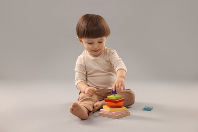 Photo of Cute little boy playing on grey background