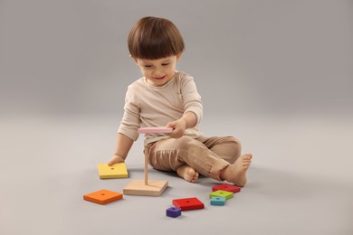 Photo of Cute little boy playing on grey background