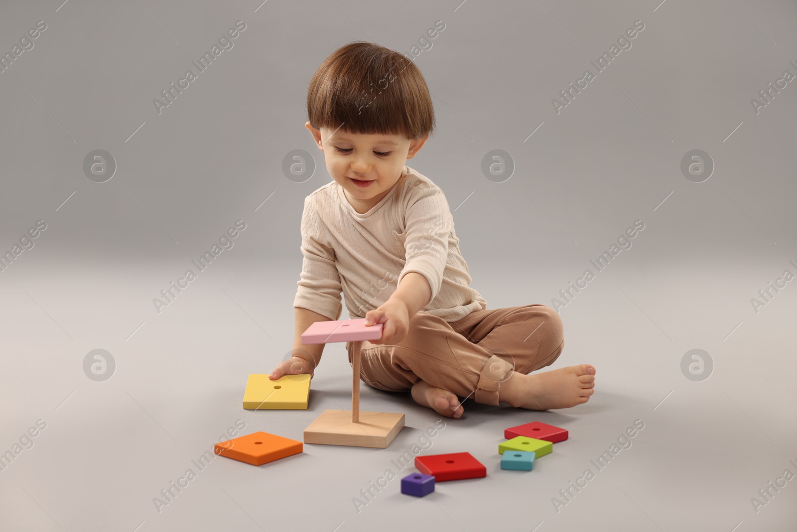 Photo of Cute little boy playing on grey background