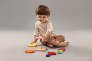 Cute little boy playing on grey background