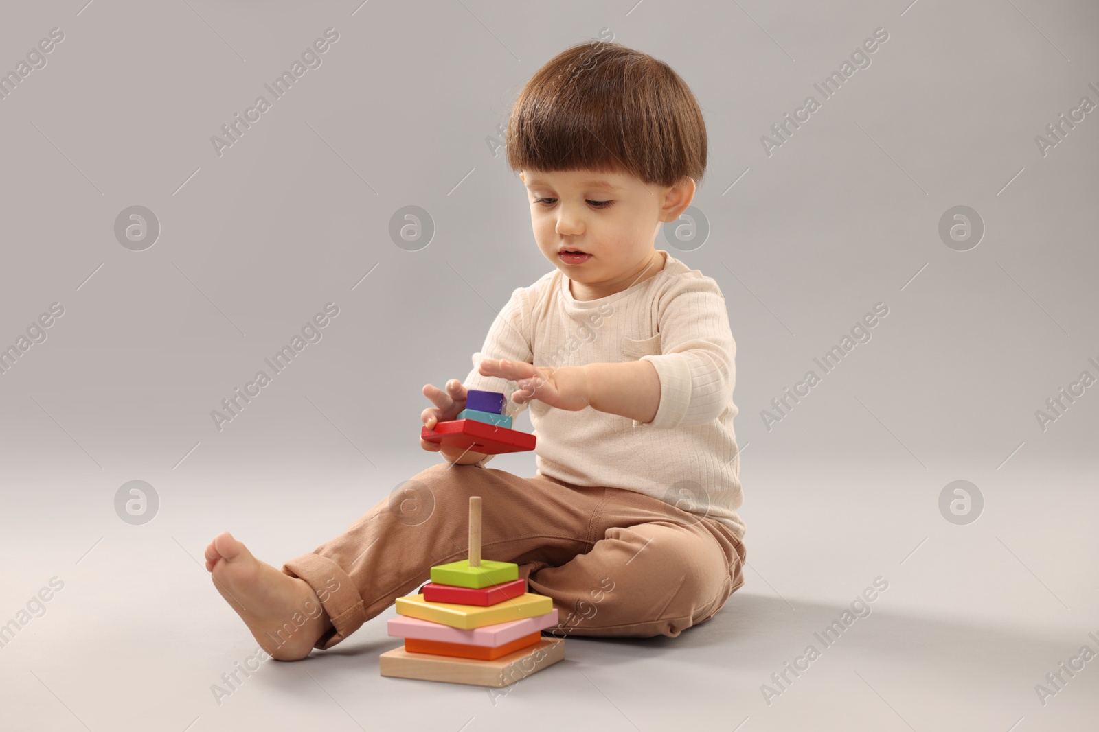 Photo of Cute little boy playing on grey background