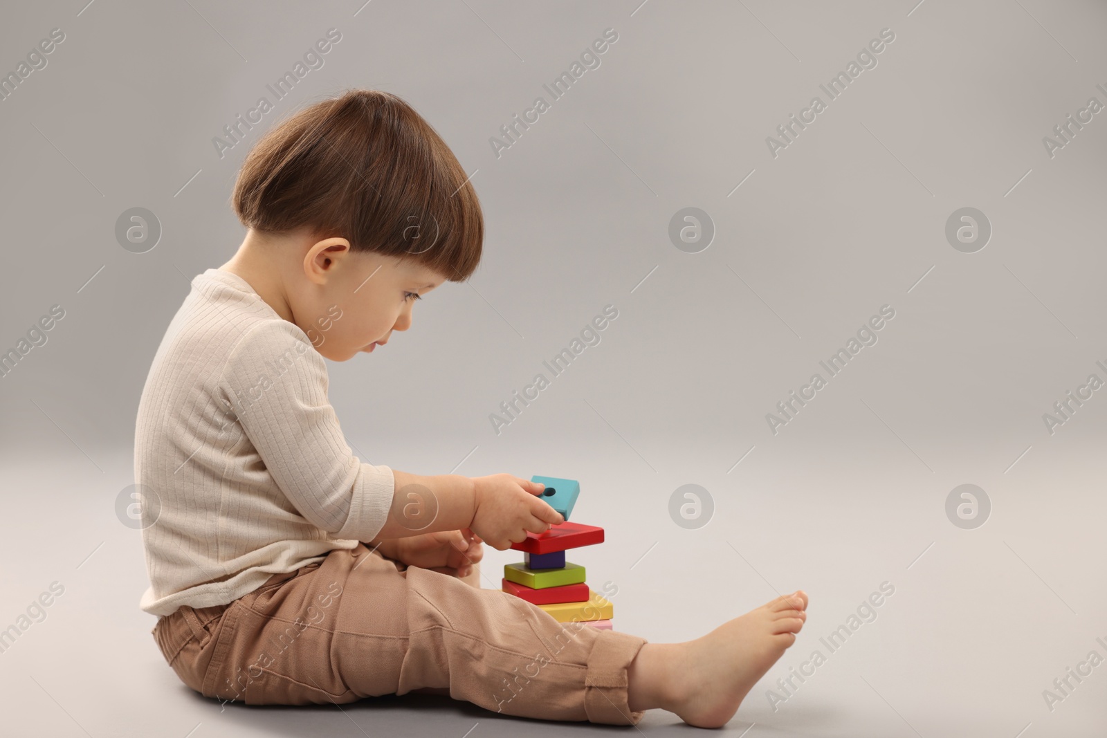 Photo of Cute little boy playing on grey background. Space for text