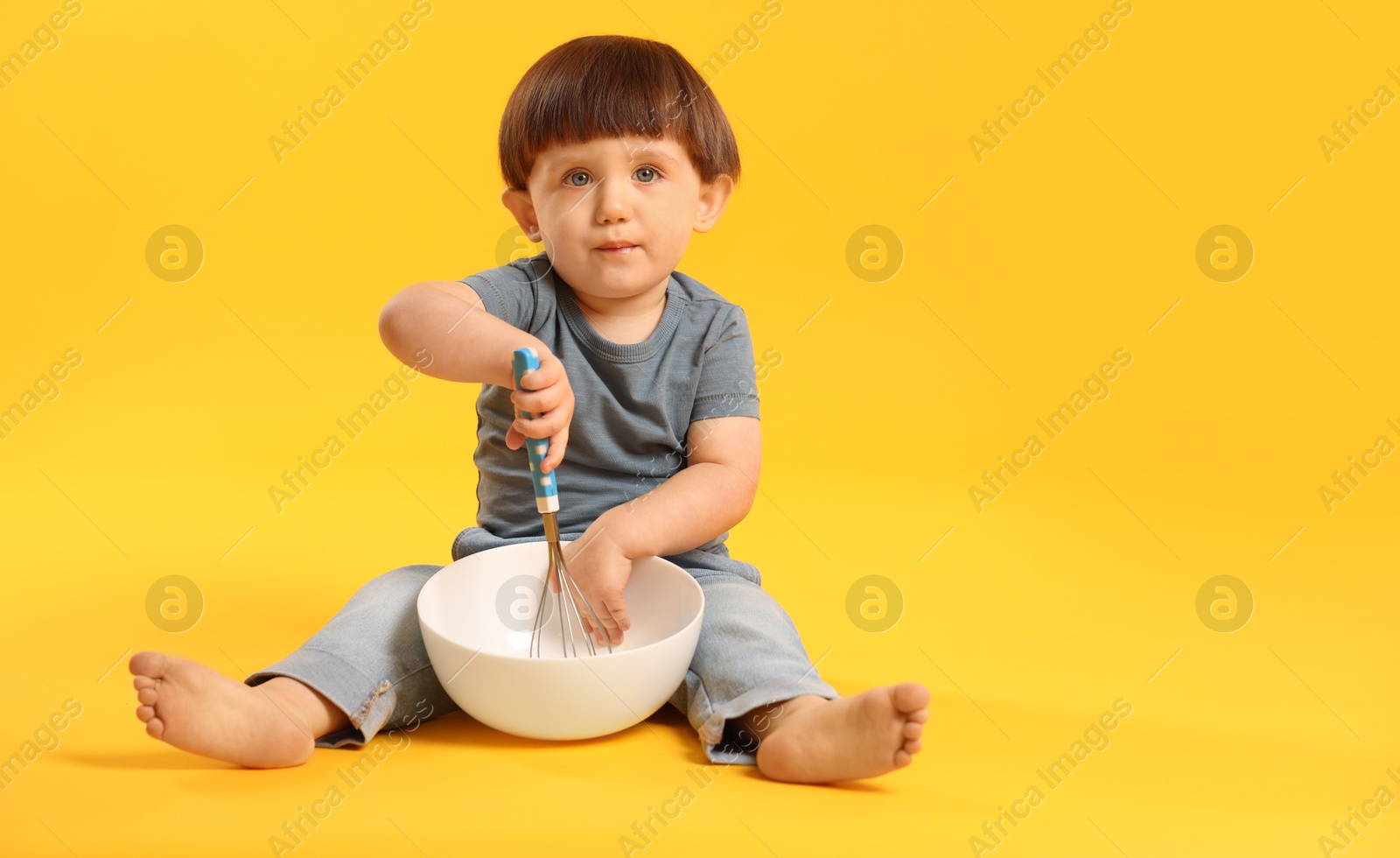 Photo of Cute little boy with bowl and whisk on yellow background. Space for text