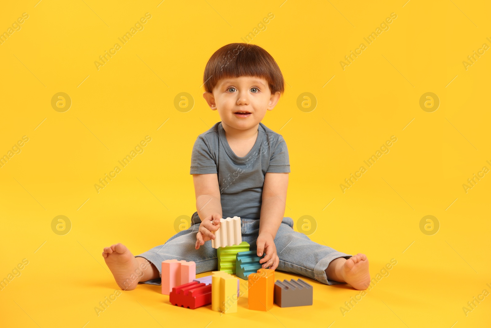 Photo of Cute little boy playing on yellow background