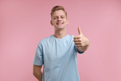 Happy man showing thumbs up on pink background. Like gesture