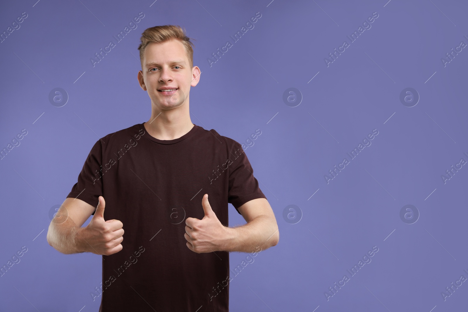 Photo of Happy man showing thumbs up on purple background, space for text. Like gesture