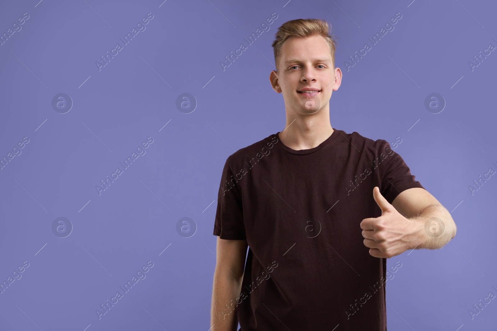 Photo of Happy man showing thumbs up on purple background, space for text. Like gesture