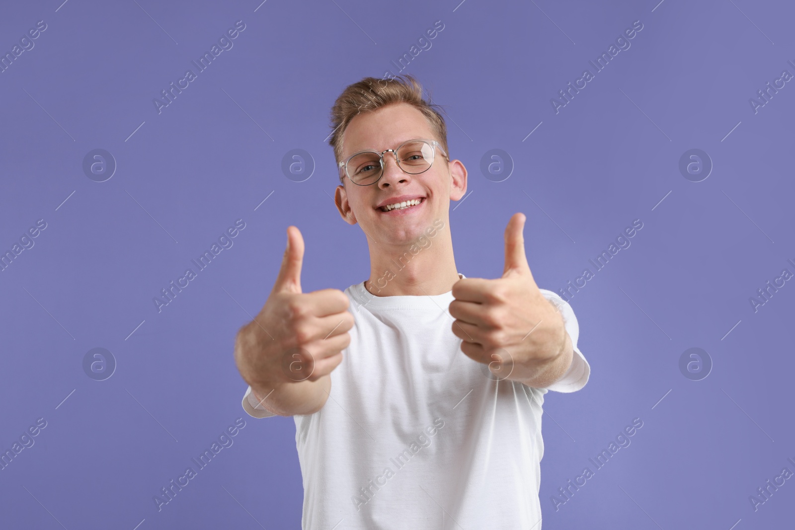 Photo of Happy man showing thumbs up on purple background. Like gesture