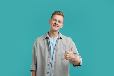 Photo of Happy man showing thumbs up on light blue background. Like gesture