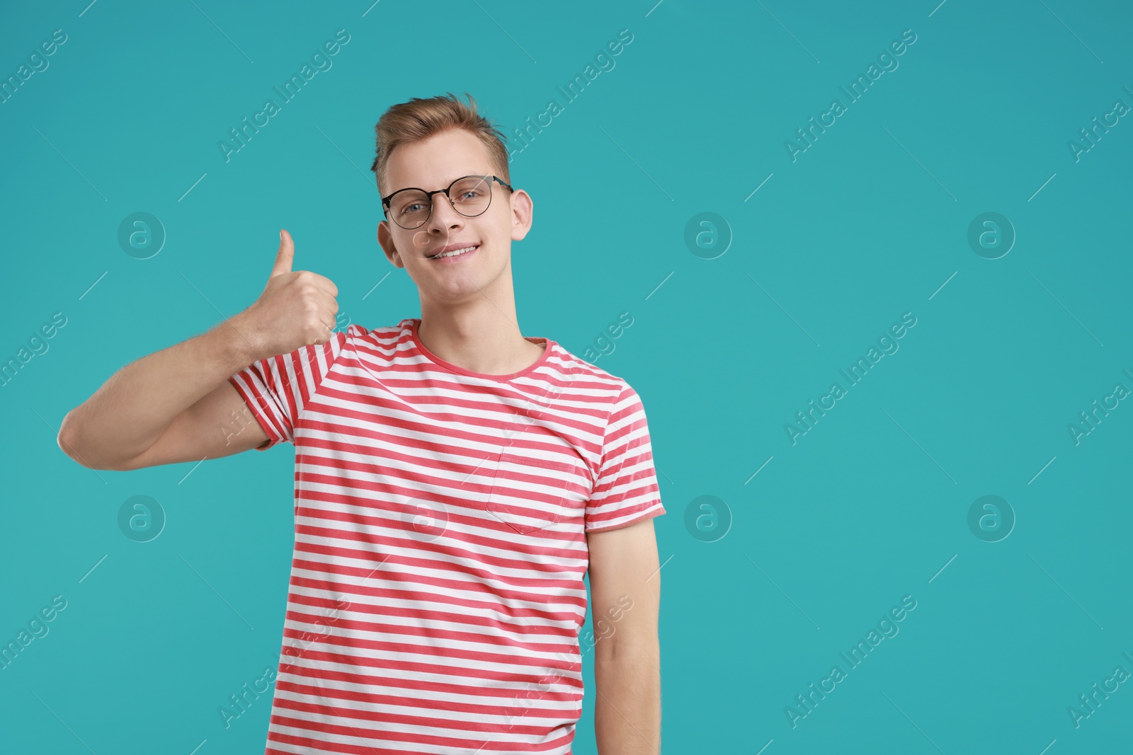 Photo of Happy man showing thumbs up on light blue background, space for text. Like gesture