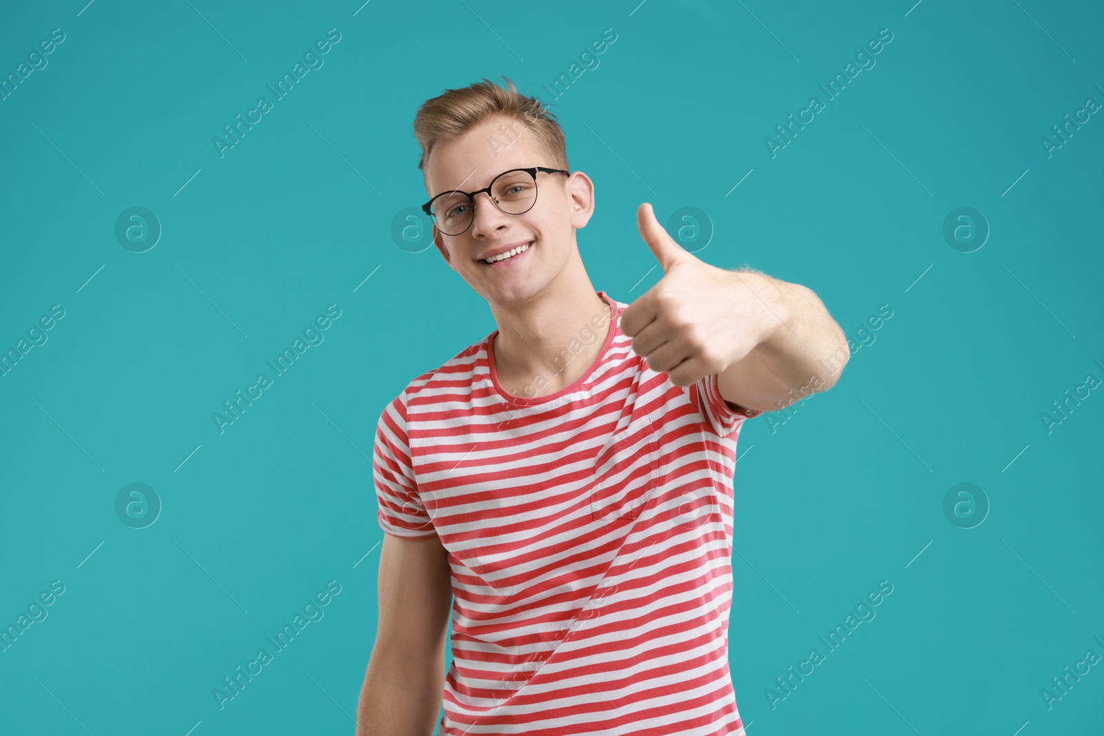 Photo of Happy man showing thumbs up on light blue background. Like gesture