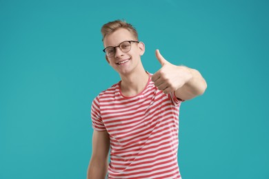 Happy man showing thumbs up on light blue background. Like gesture