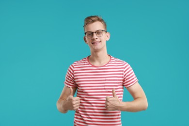 Photo of Happy man showing thumbs up on light blue background. Like gesture