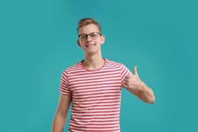 Photo of Happy man showing thumbs up on light blue background. Like gesture