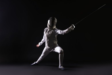 Photo of Fencer with epee practicing on dark background