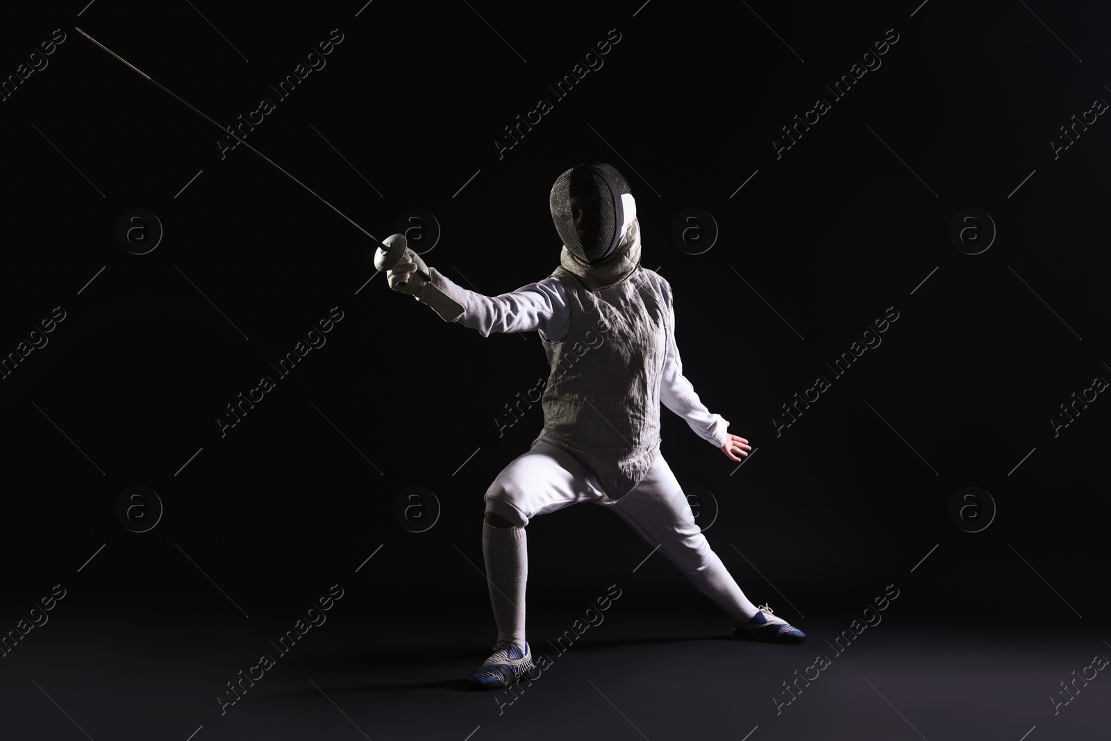 Photo of Fencer with epee practicing on dark background