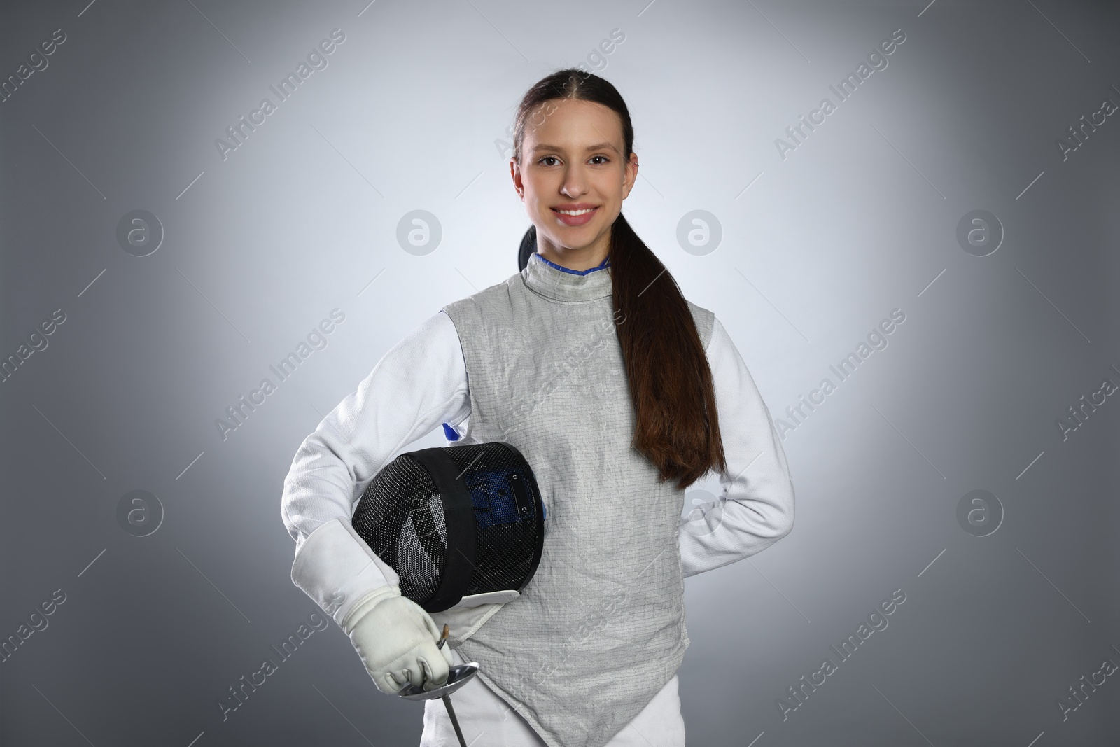 Photo of Smiling fencer with epee on gray background