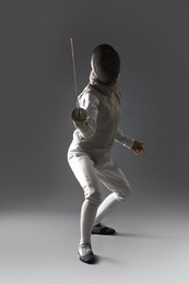 Photo of Fencer with epee practicing on gray background