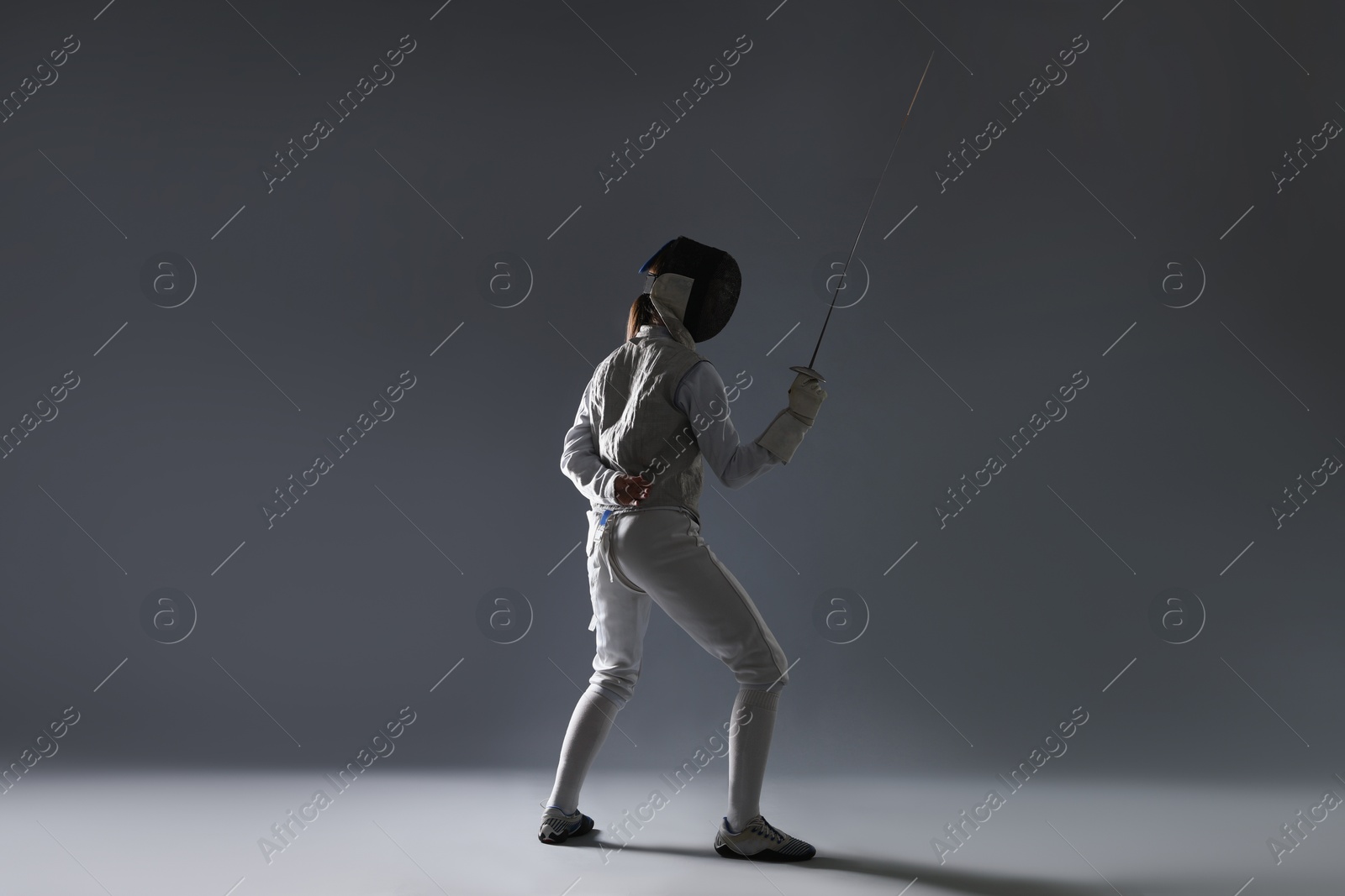 Photo of Fencer with epee on gray background. Combat sport