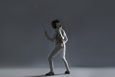 Photo of Fencer with epee on gray background. Combat sport