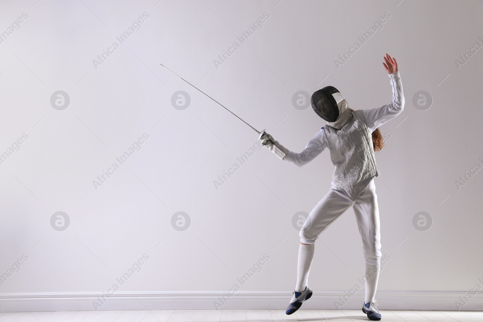 Photo of Fencer with epee practicing indoors, space for text