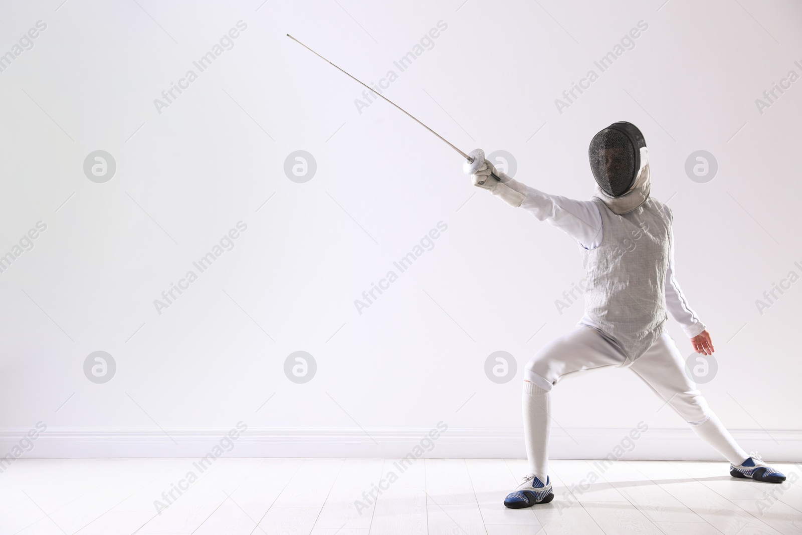 Photo of Fencer with epee practicing indoors, space for text