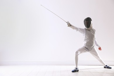 Photo of Fencer with epee practicing indoors, space for text