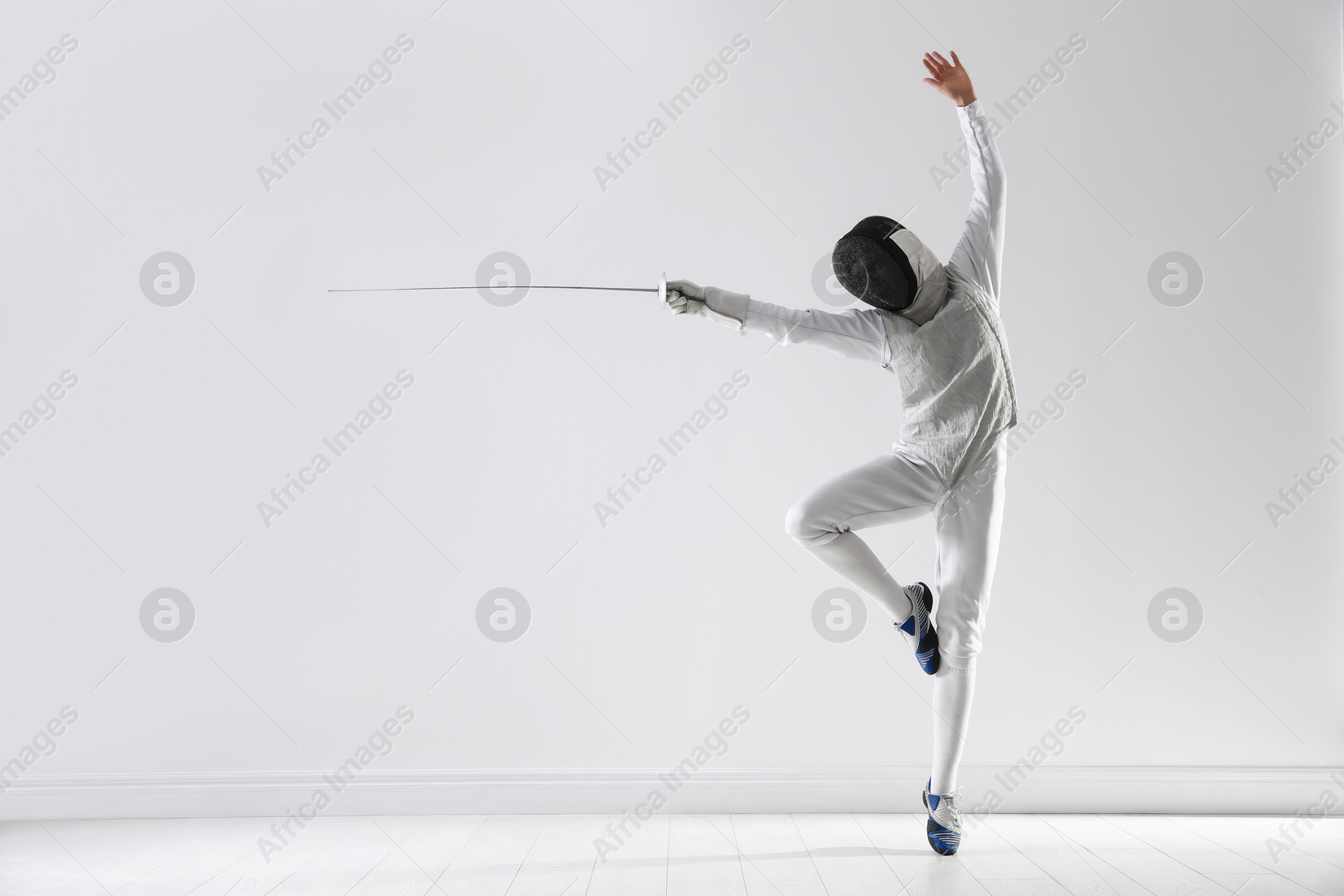 Photo of Fencer with epee practicing indoors, space for text