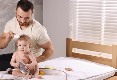 Man brushing hair of his little baby on bed indoors, space for text