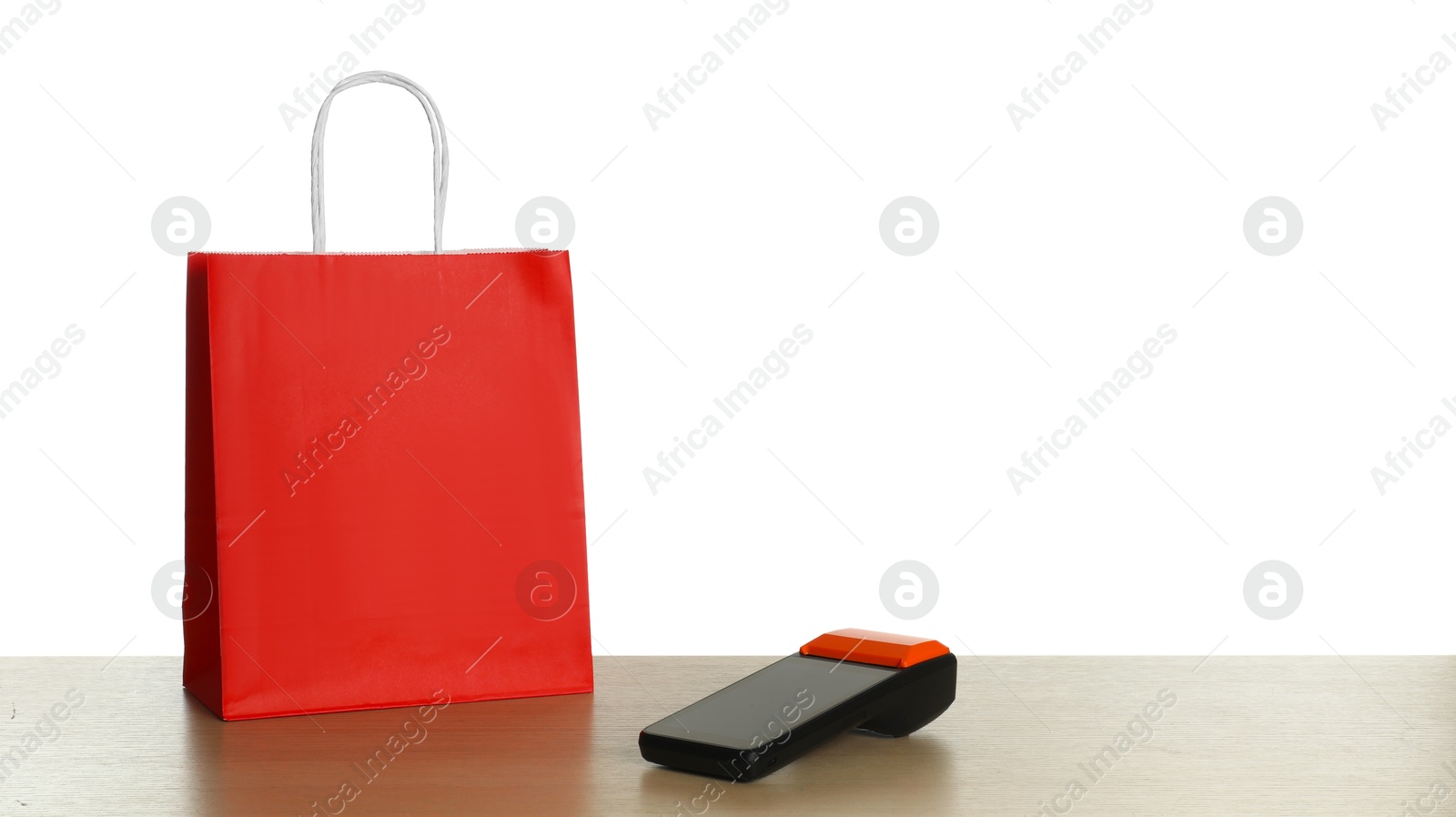 Photo of Payment terminal and shopping bag on wooden table against white background