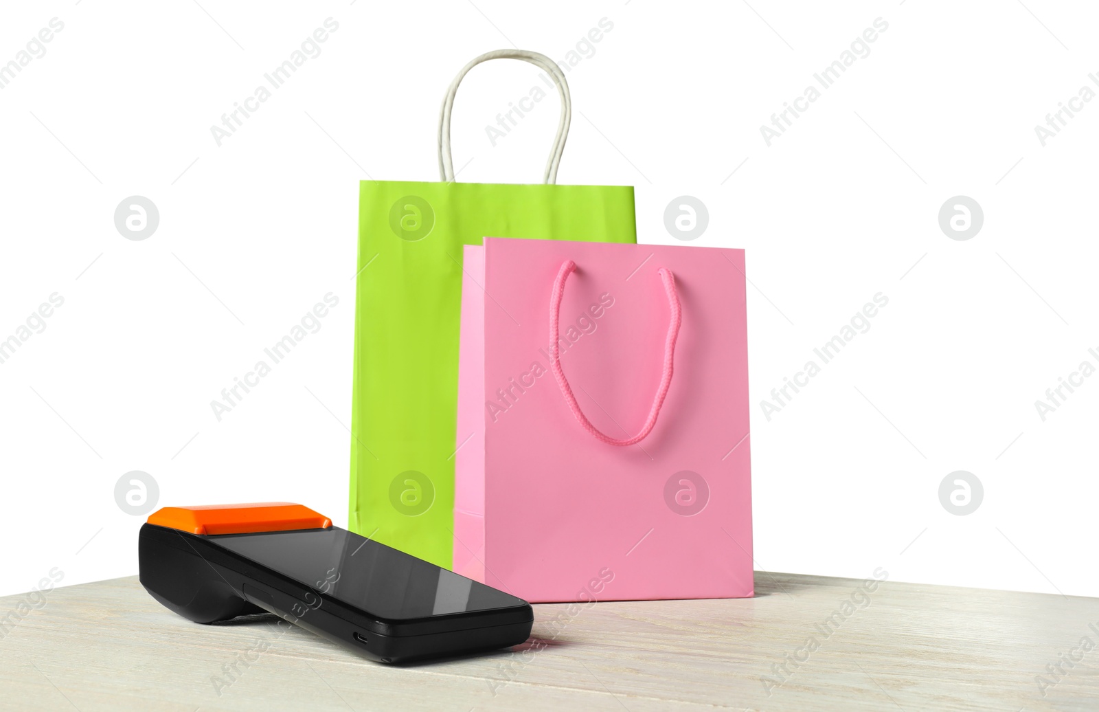 Photo of Payment terminal and shopping bags on wooden table against white background