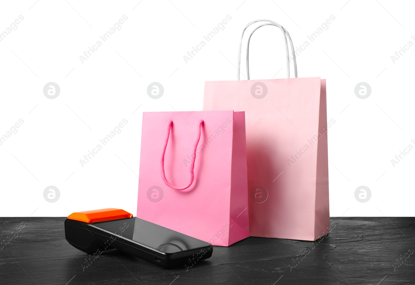 Photo of Payment terminal and shopping bags on black table against white background