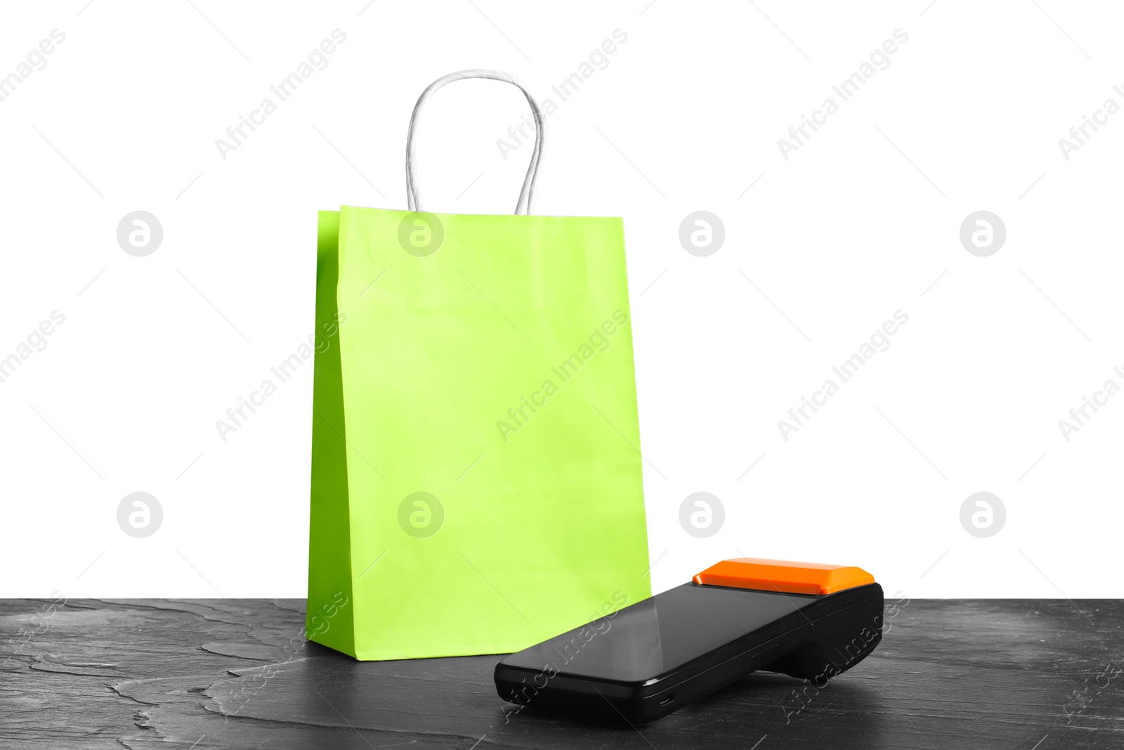 Photo of Payment terminal and shopping bag on black table against white background